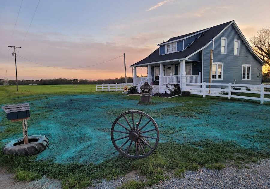 how to start a hydroseeding business - a farmhouse sits in the distances in front of a grassy lawn with green hydroseed sprayed on it.